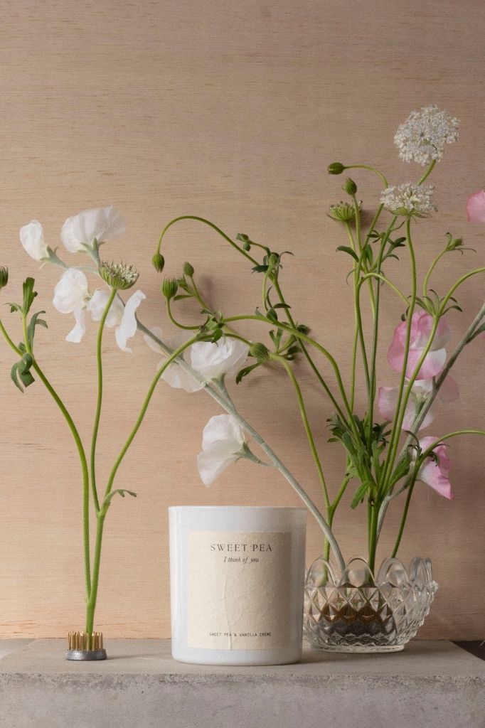 The Sweet Pea candle beside a cut-glass vase of white and pink sweet peas.
