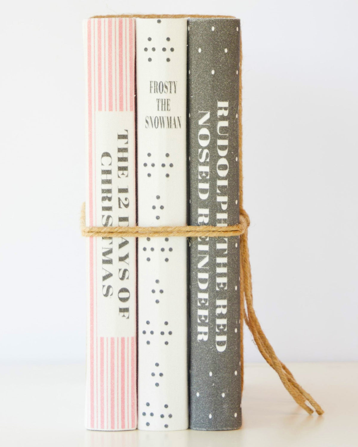 Spines of the three Christmas book stack titles - Frosty the Snowman, 12 Days of Christmas, Rudolph