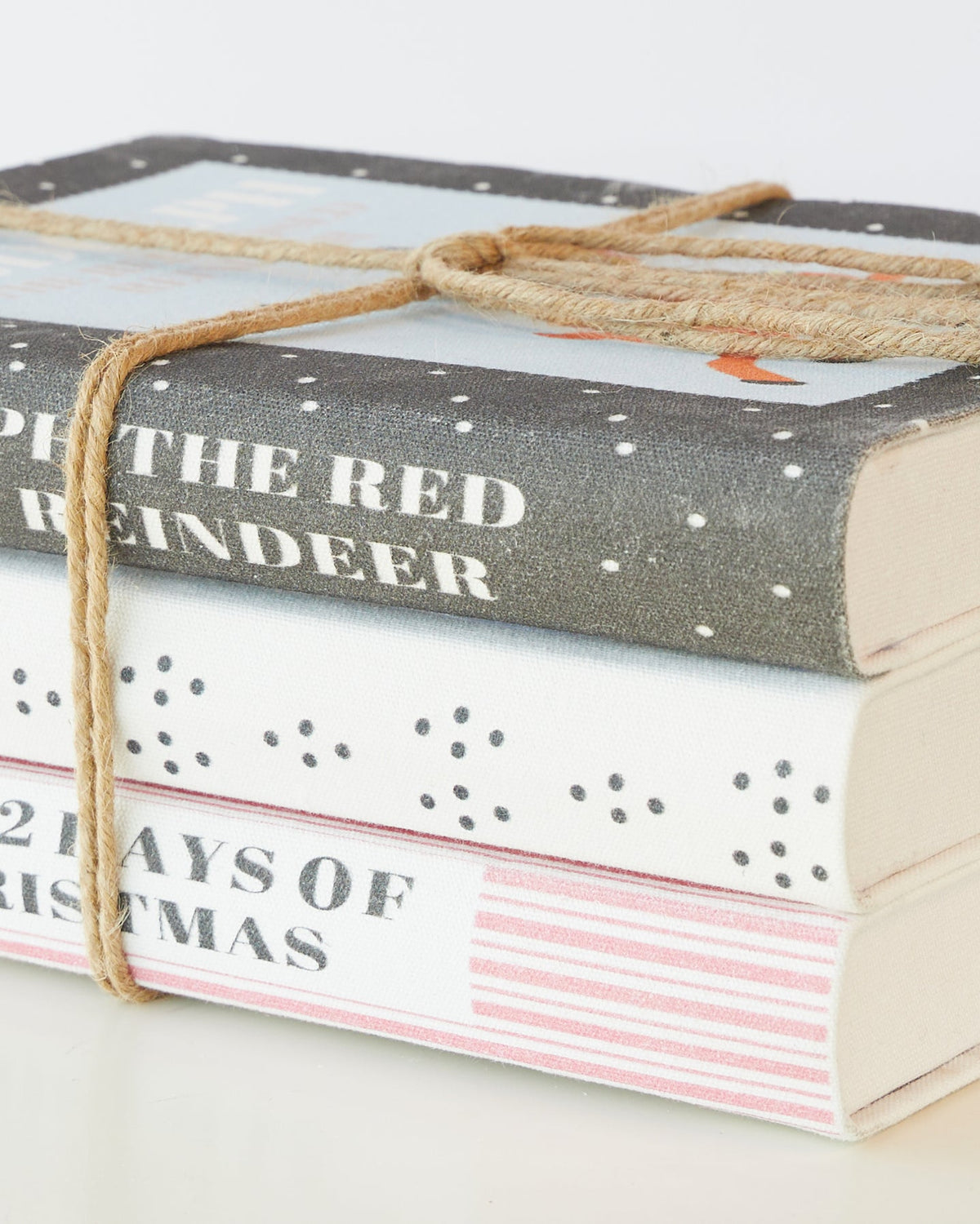 Close view of the tied Christmas book stack showing the grey spotted and pink striped covers