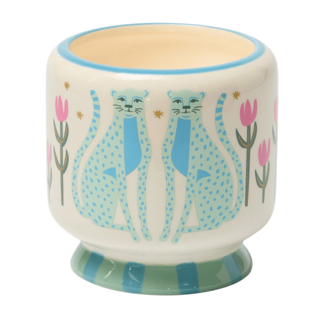 The Blue Cheetahs candle close up: blue cheetahs and pink tulips on a cream ceramic pot.