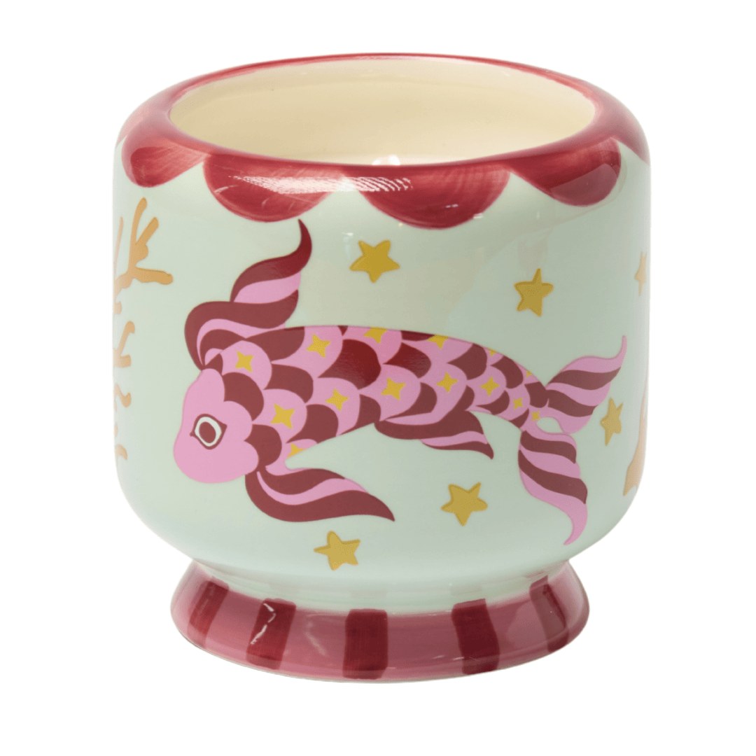 The Koi candle close up: a pink koi and gold stars hand-painted on a mint ceramic pot.