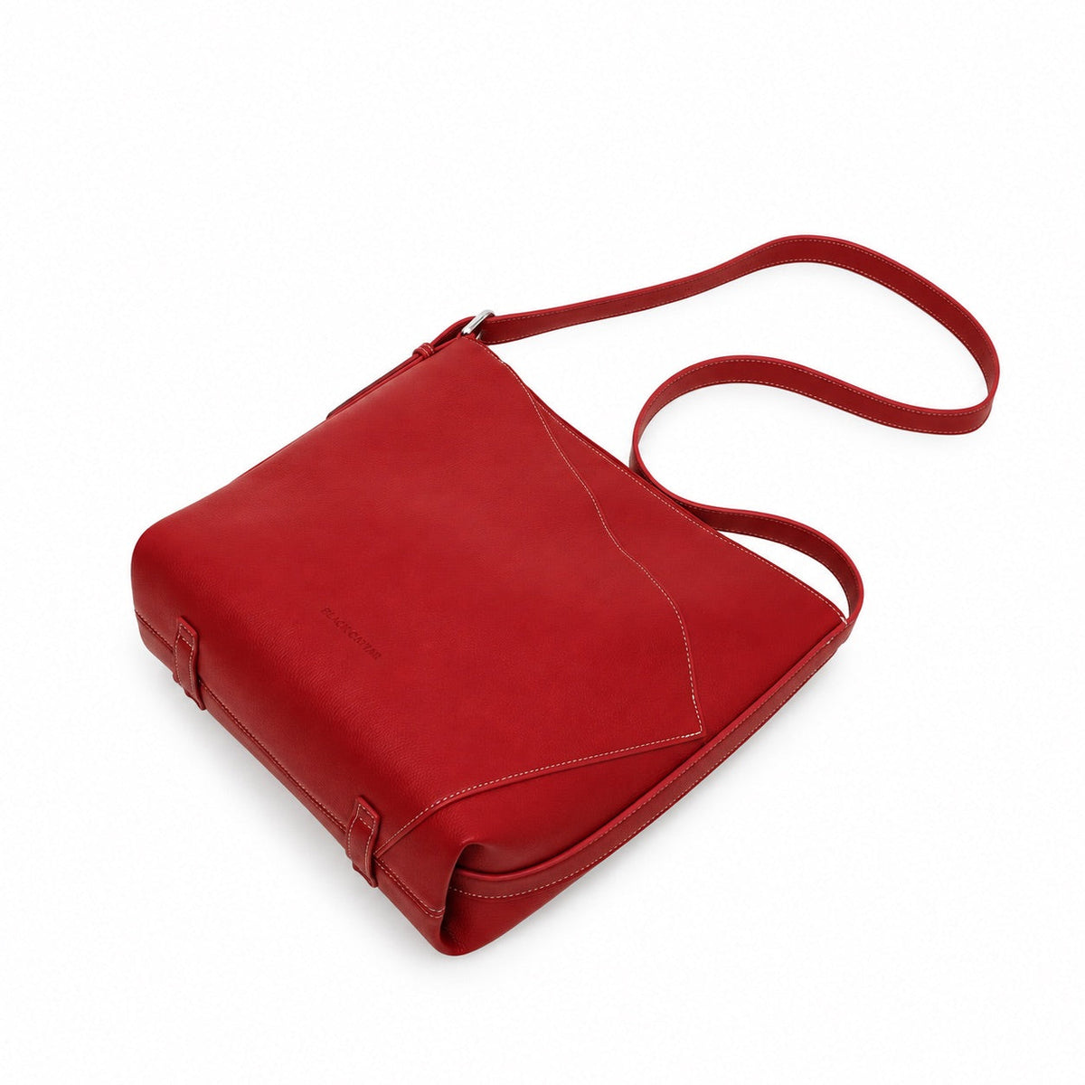 The red shoulder bag lying on its side with the strap looped above it.