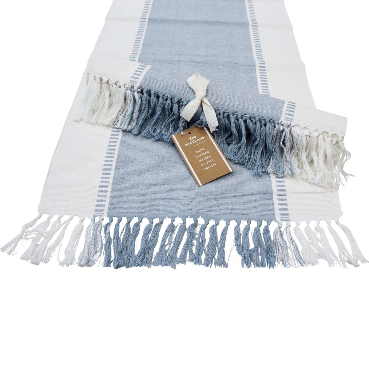 Chambray Blue and white table runner laid flat with blue and white tassels, a second runner rolled and tied with a ribbon on top