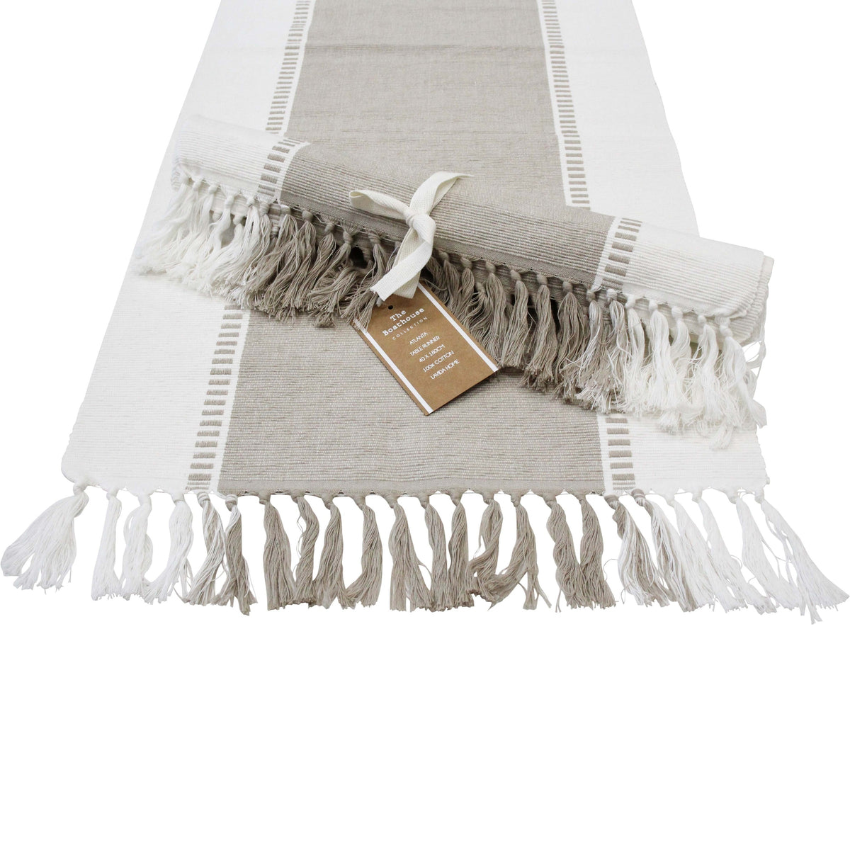Natural taupe and white table runner laid flat with taupe and white tassels, a second runner rolled and tied with a ribbon on top