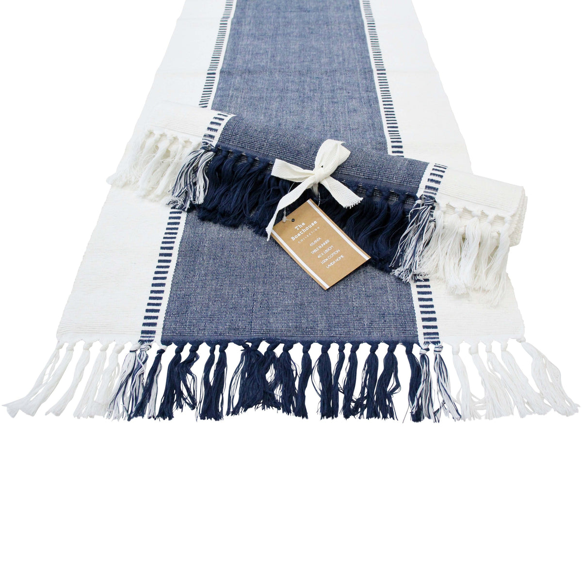Navy and white table runner laid flat with navy and white tassels, a second runner rolled and tied with a ribbon on top