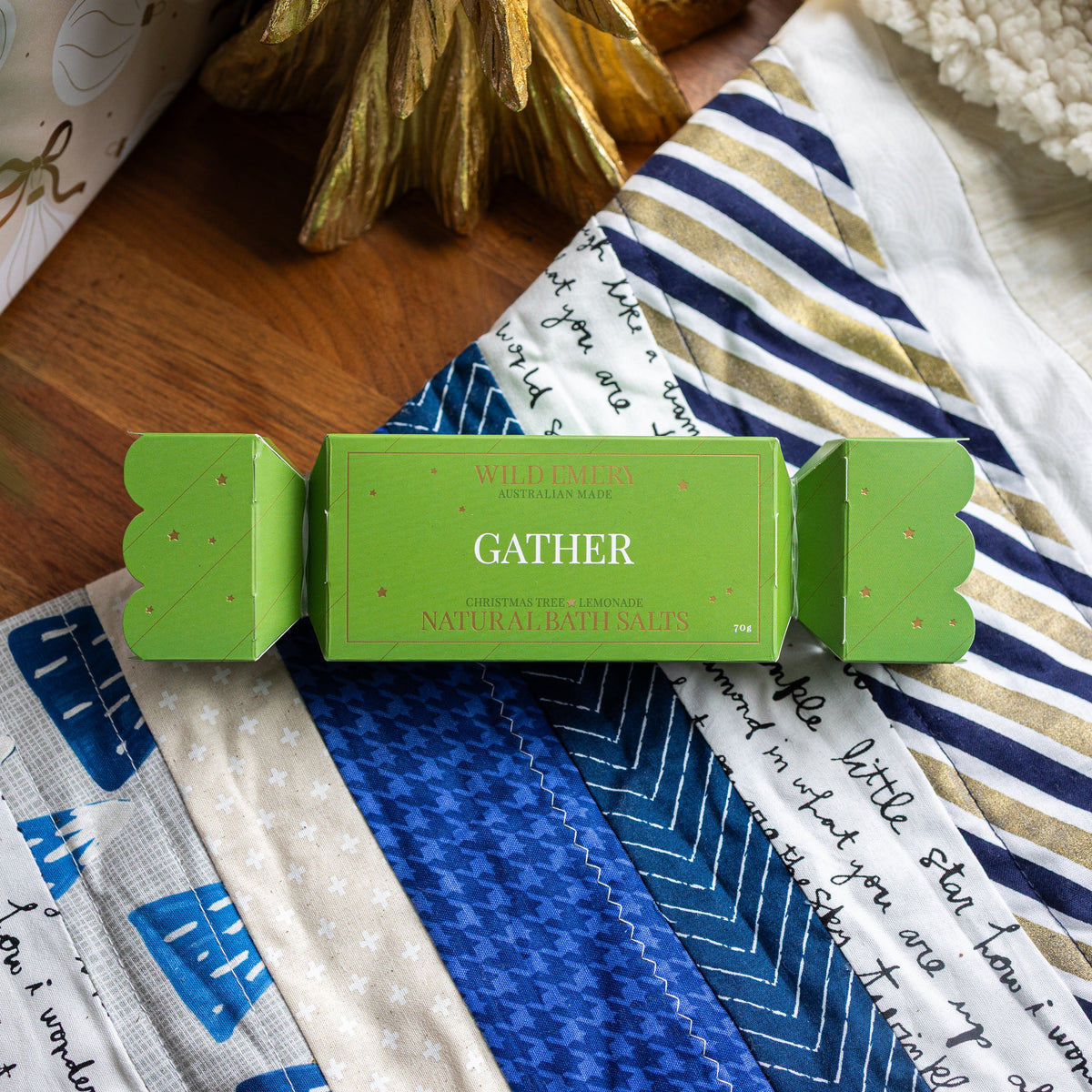 Green Gather bath salt bon bon, shaped like a Christmas cracker, on a patchwork quilt.