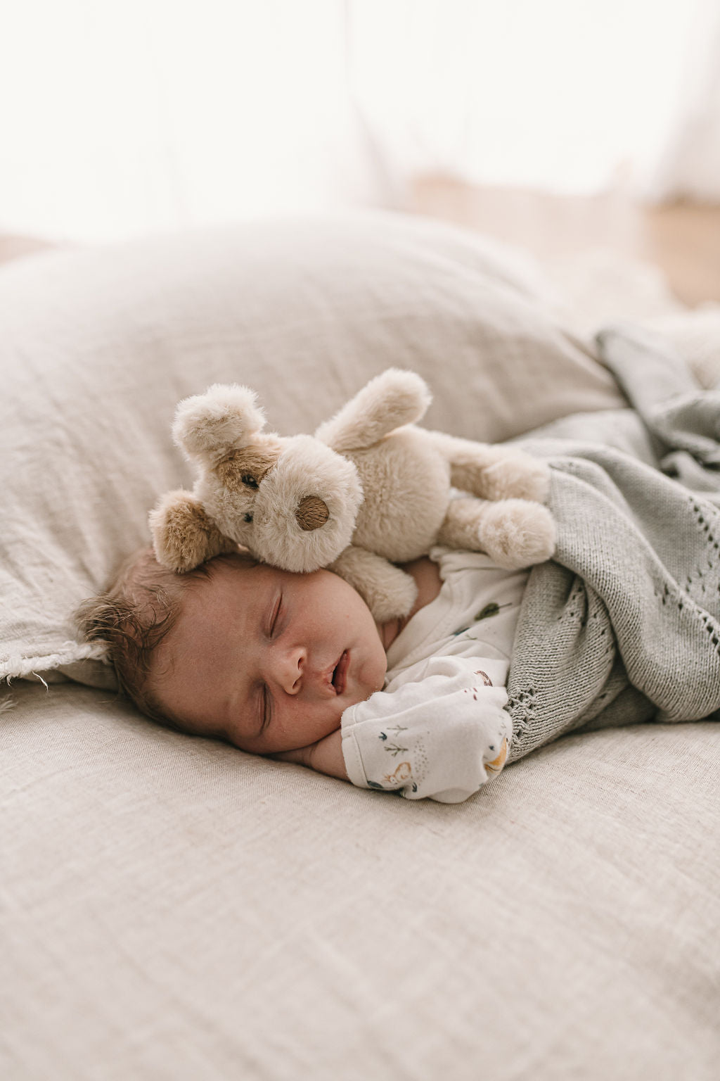 A sleeping baby on a pillow with the little dog resting against their shoulder.