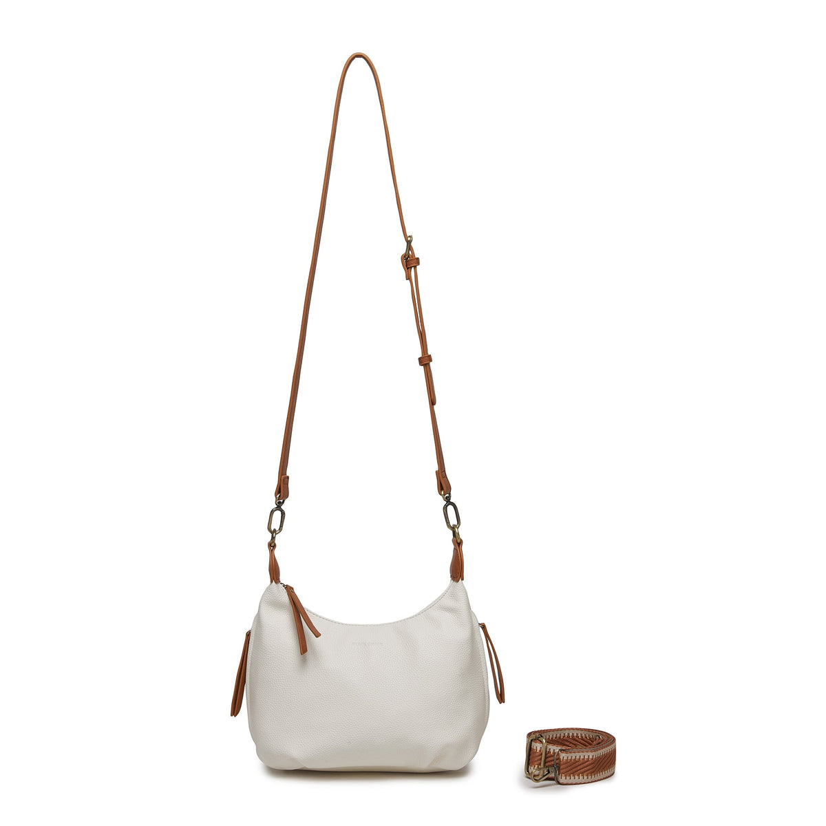 The white bag on its long tan cross body strap, with the patterned cotton strap coiled beside it.