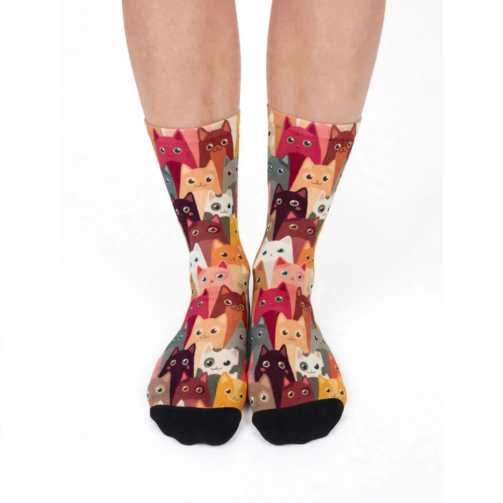 Crew socks worn on a pair of feet, printed edge to edge with rows of cat faces in red, orange, pink, cream and brown.