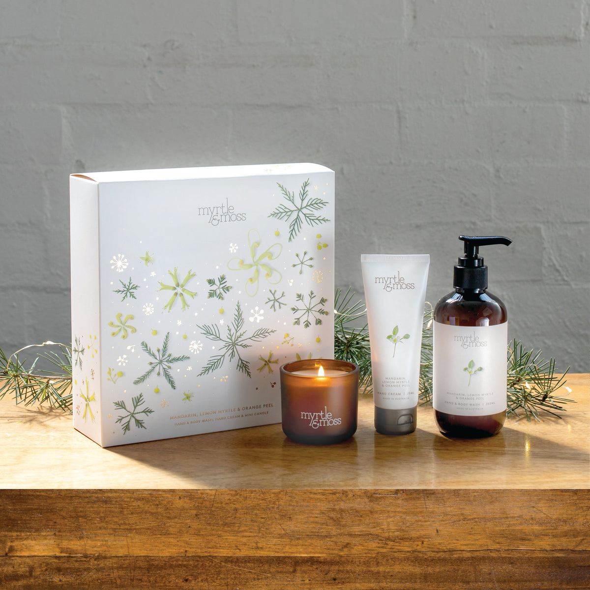 Myrtle & Moss Citrus Christmas gift box with the mini candle, 75 mL hand cream and 250 mL amber pump bottle of hand and body wash in front.