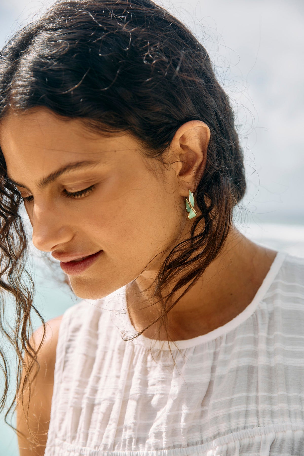 Close view of a Lime Coast Twist hoop worn by a model with dark hair