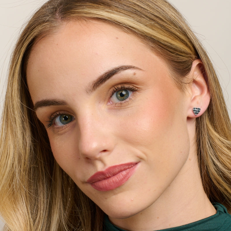 Model in a green top wearing the black gingham heart studs
