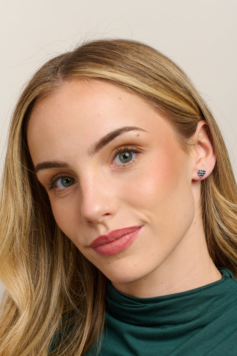 Model in a green top wearing the black gingham heart studs