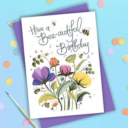 Card lettered Have a Bee-autiful Birthday above purple and yellow flowers and bees, on a purple envelope