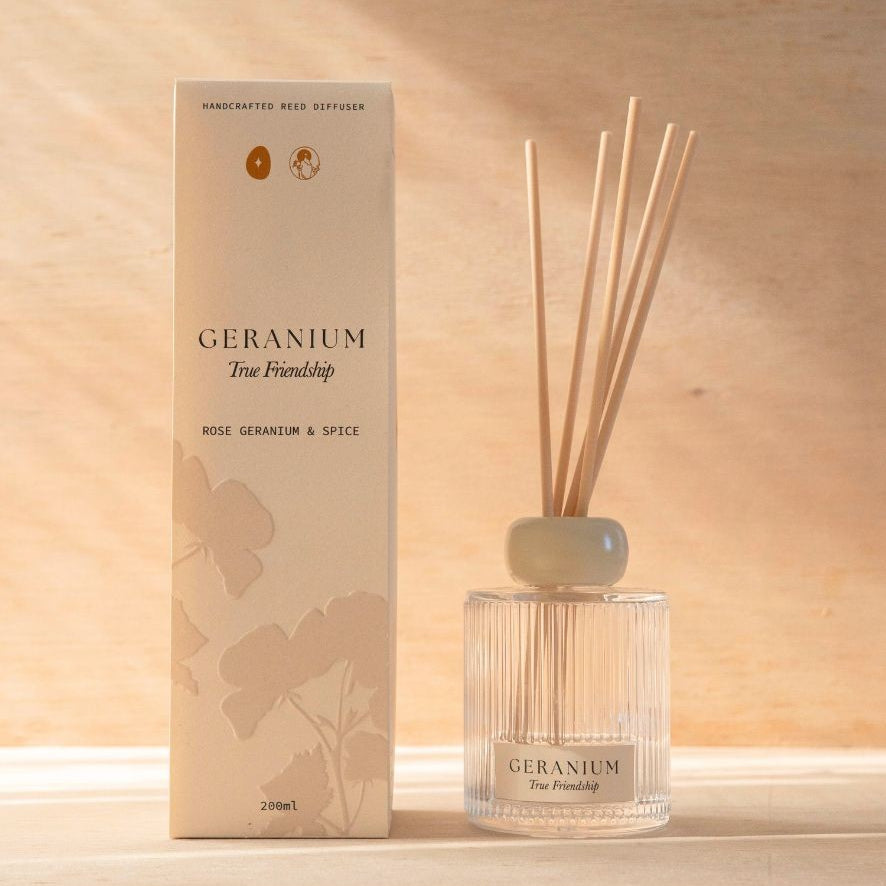 The Geranium reed diffuser, a ribbed glass bottle with natural reeds, beside its cream box.