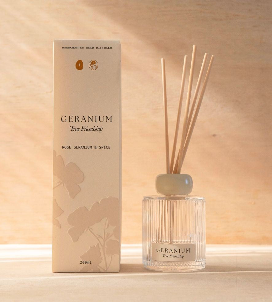 The Geranium reed diffuser, a ribbed glass bottle with natural reeds, beside its cream box.