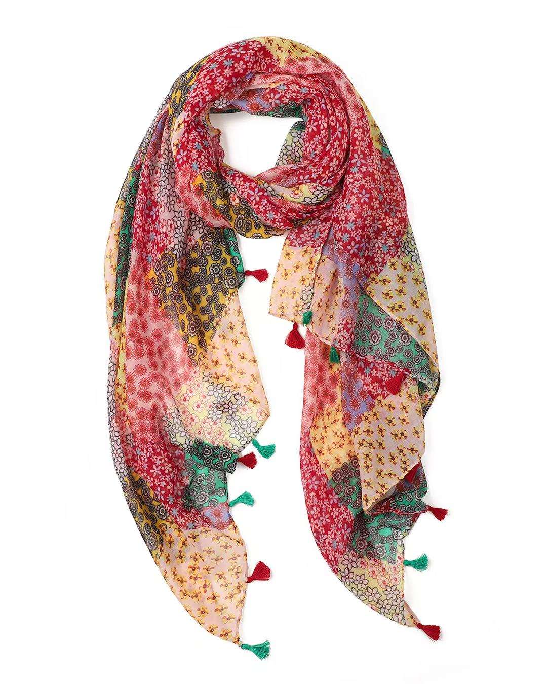 Lightweight scarf in a red and pink patchwork of small floral prints, looped to show the red and green tassels.