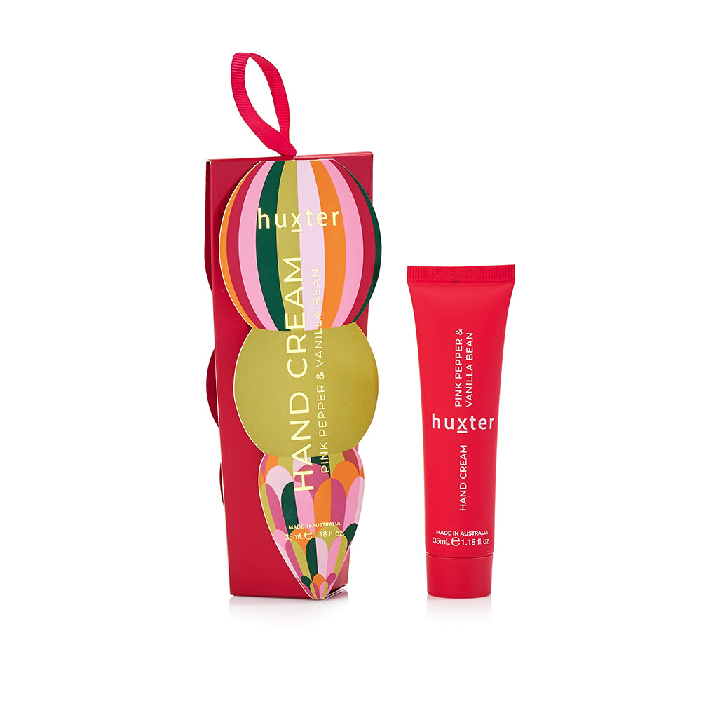 Red Huxter hanging hand cream box with a striped bauble and ribbon loop, beside the red Pink Pepper & Vanilla Bean tube.