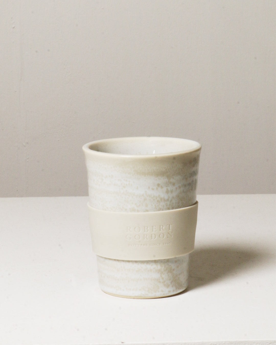 The Coast carousel cup with its silicone band, on a pale surface.