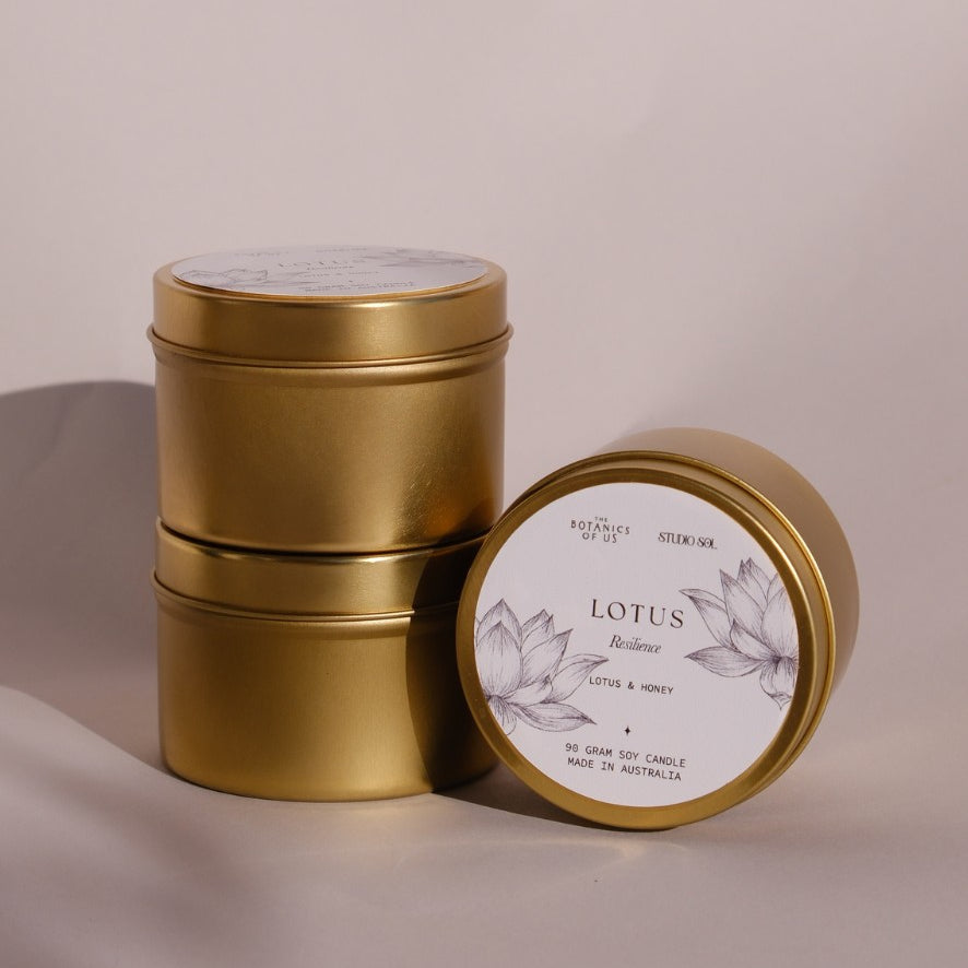 Three gold Lotus travel tins, one tipped forward to show its lid label with a drawing of the lotus.