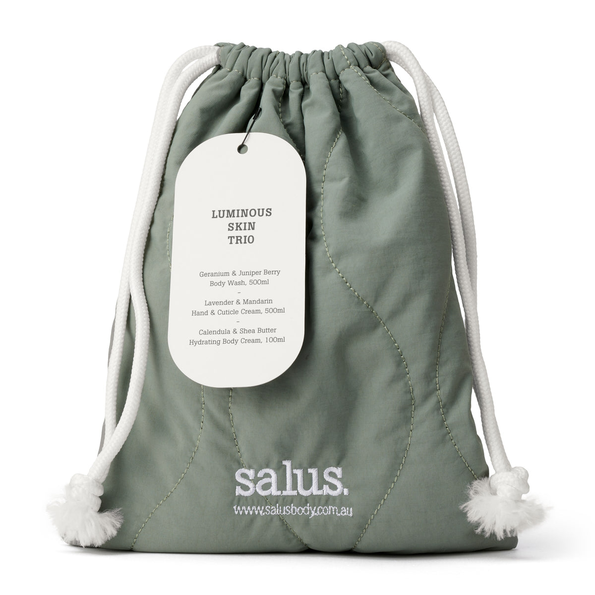 Quilted sage-green Salus drawstring bag with white cord ties and a tag reading Luminous Skin Trio.