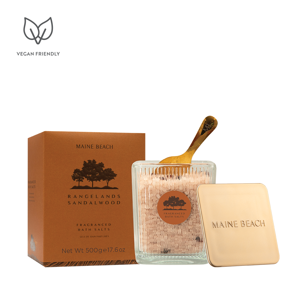 Rangelands Sandalwood Bath Salts in a glass jar with a gold scoop, beside its metal lid and orange box
