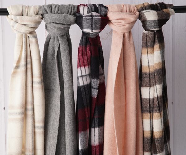Five merino wool scarves hanging side by side in cream, grey, burgundy check, blush and dark check