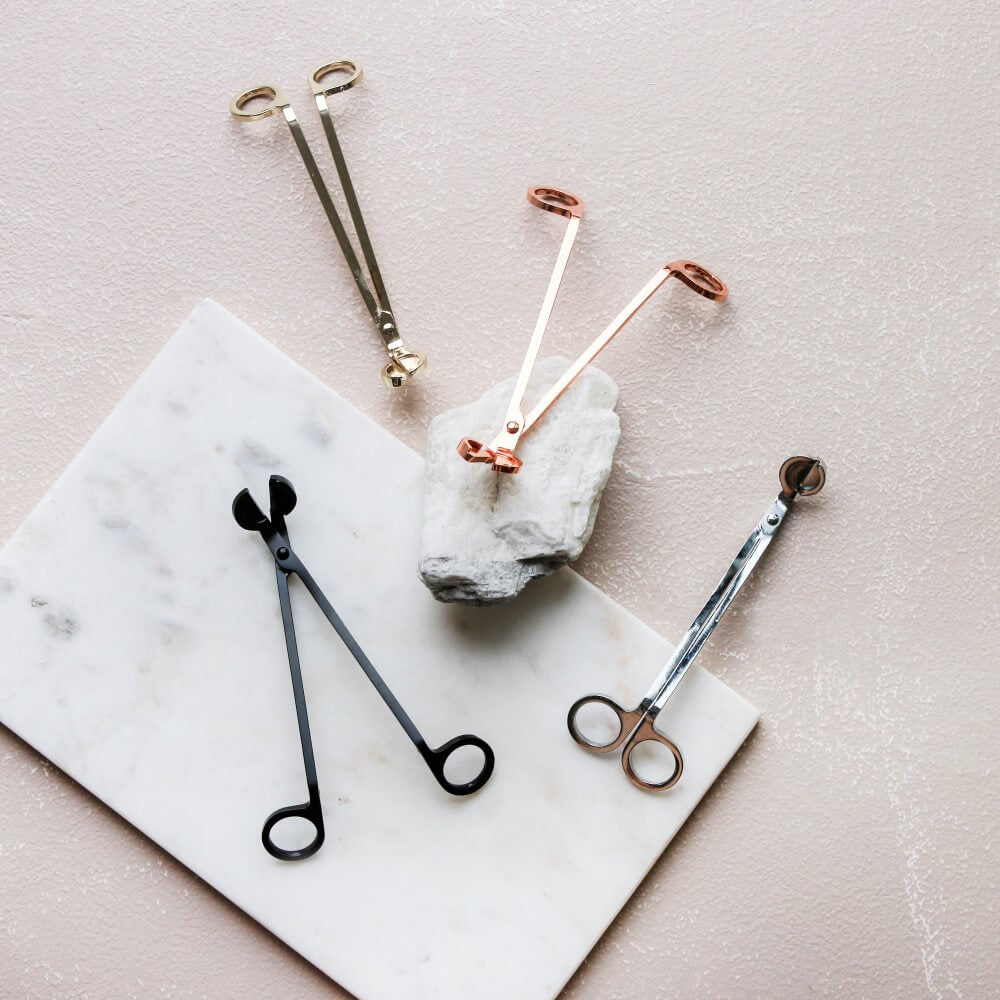 Mojo wick trimmers in gold, rose gold, black and silver on a marble board