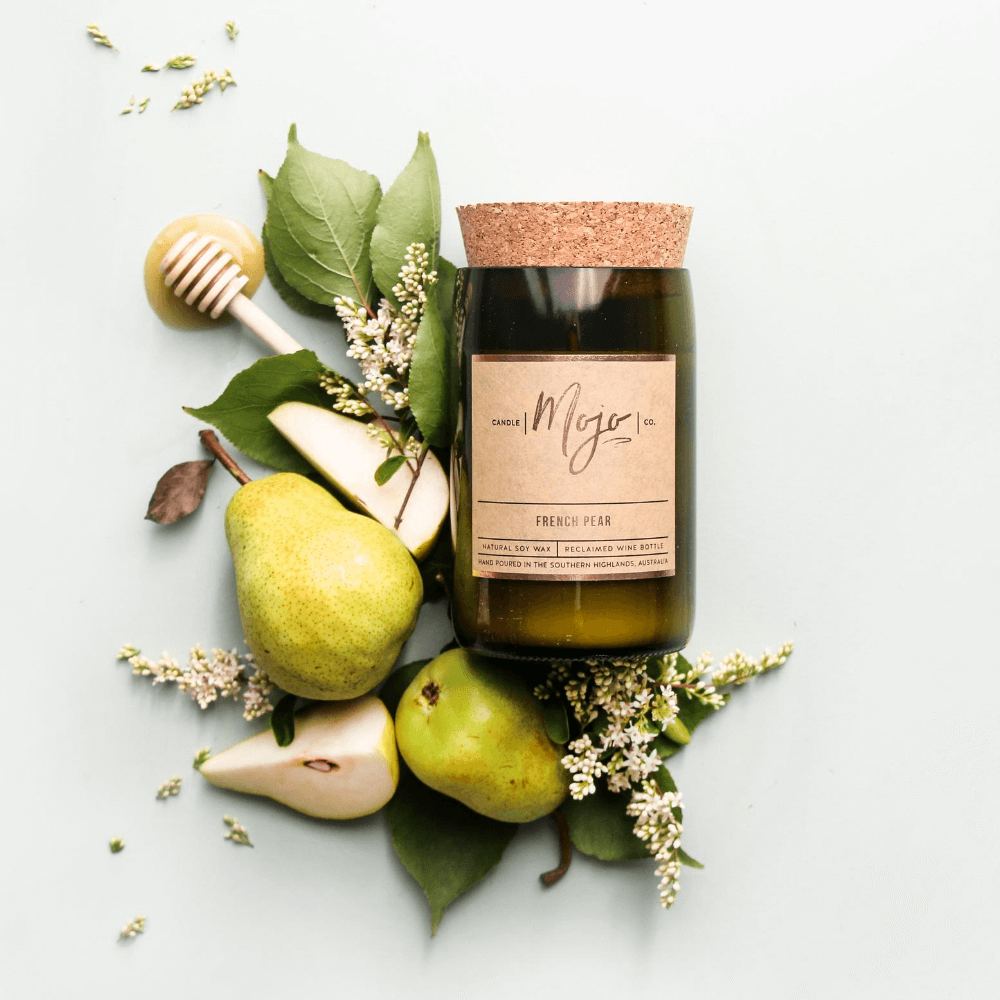 French Pear soy candle in a cork-topped reclaimed wine bottle with fresh pears, blossom and a honey dipper