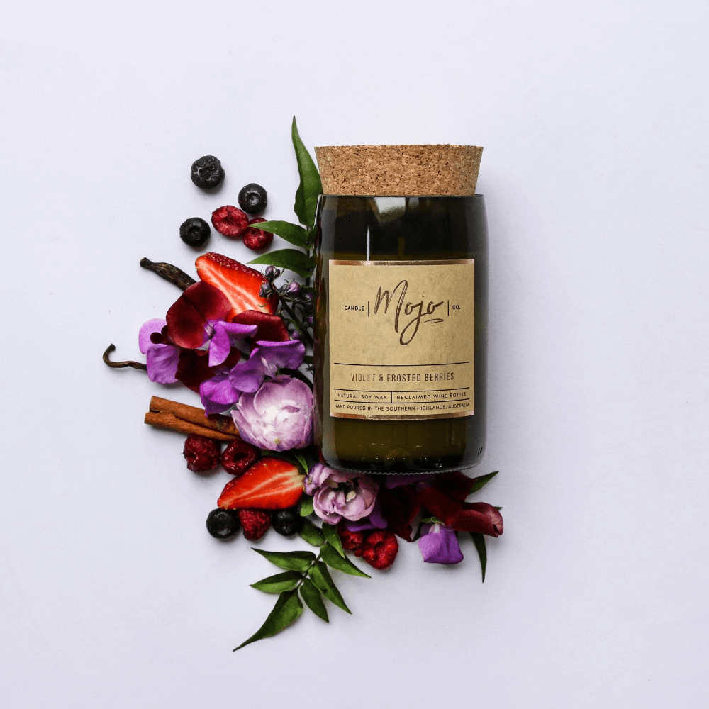 Violet & Frosted Berries soy candle in a cork-topped reclaimed wine bottle with berries, violets and vanilla pods