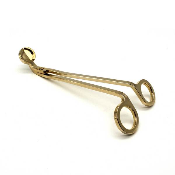 Gold stainless wick trimmer on a cream background