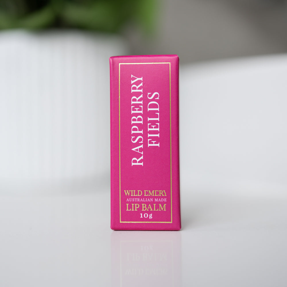 Slim pink box of Raspberry Fields lip balm standing on a white surface.