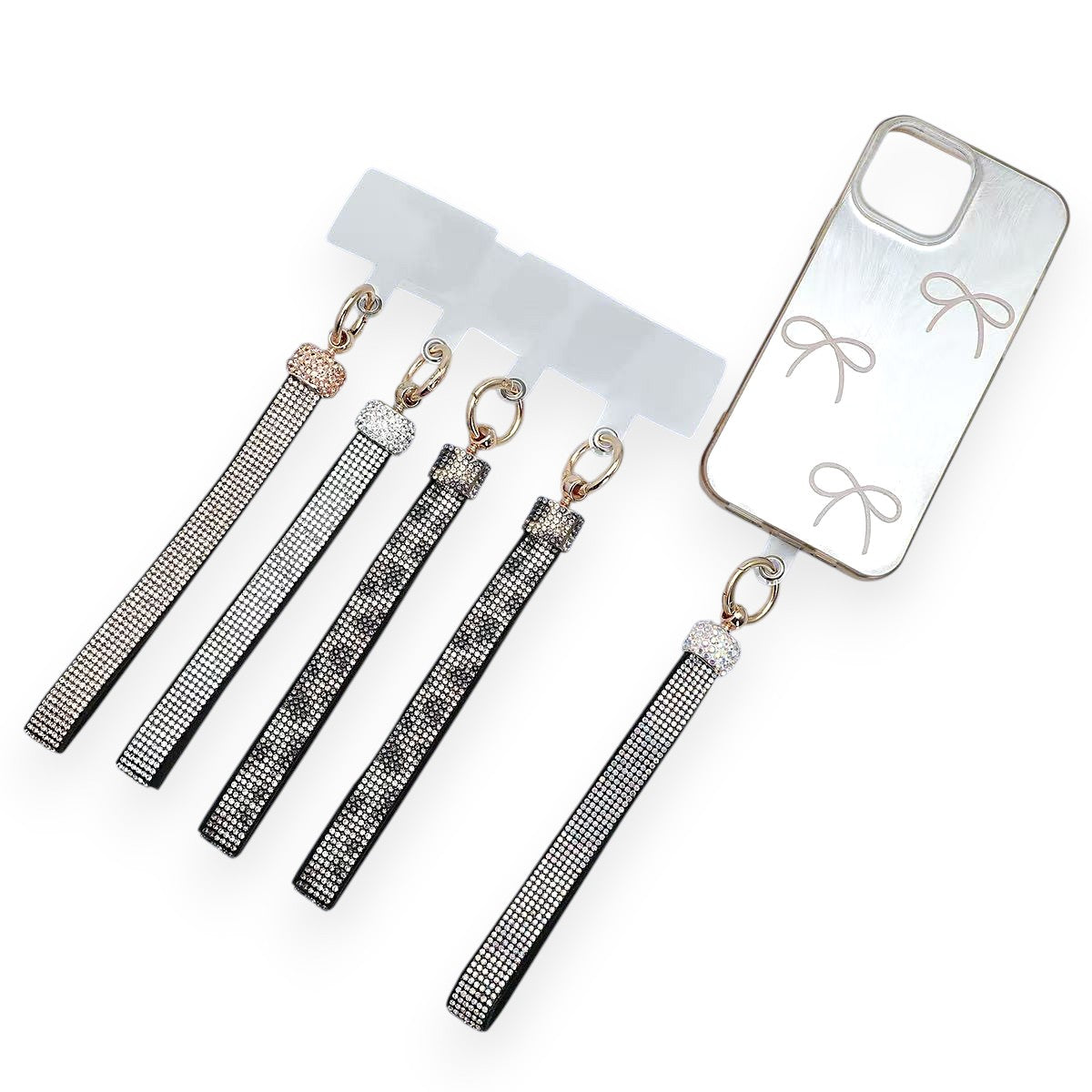 Five crystal-set phone wrist straps with clear attachment tabs, beside a phone case with a bow print