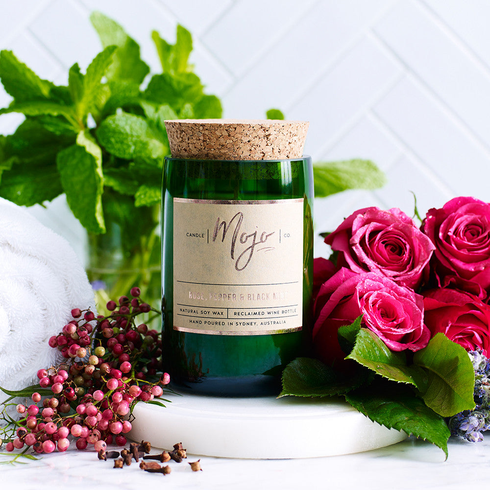 Rose, Pepper & Blackmint candle in a green reclaimed wine bottle with mint, roses and pink peppercorns
