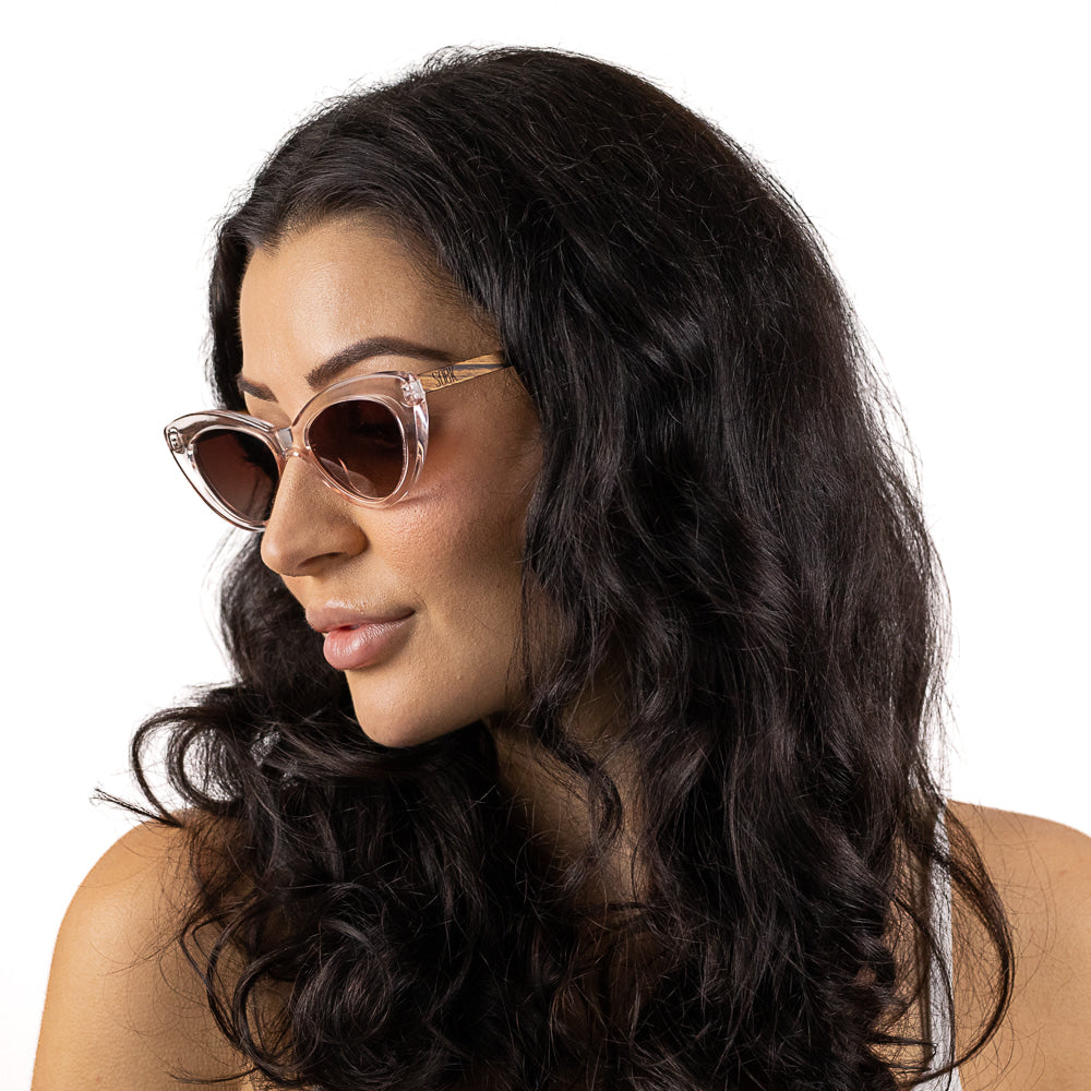 A woman with long dark wavy hair in three-quarter profile wearing the Savannah Blush Pink sunglasses