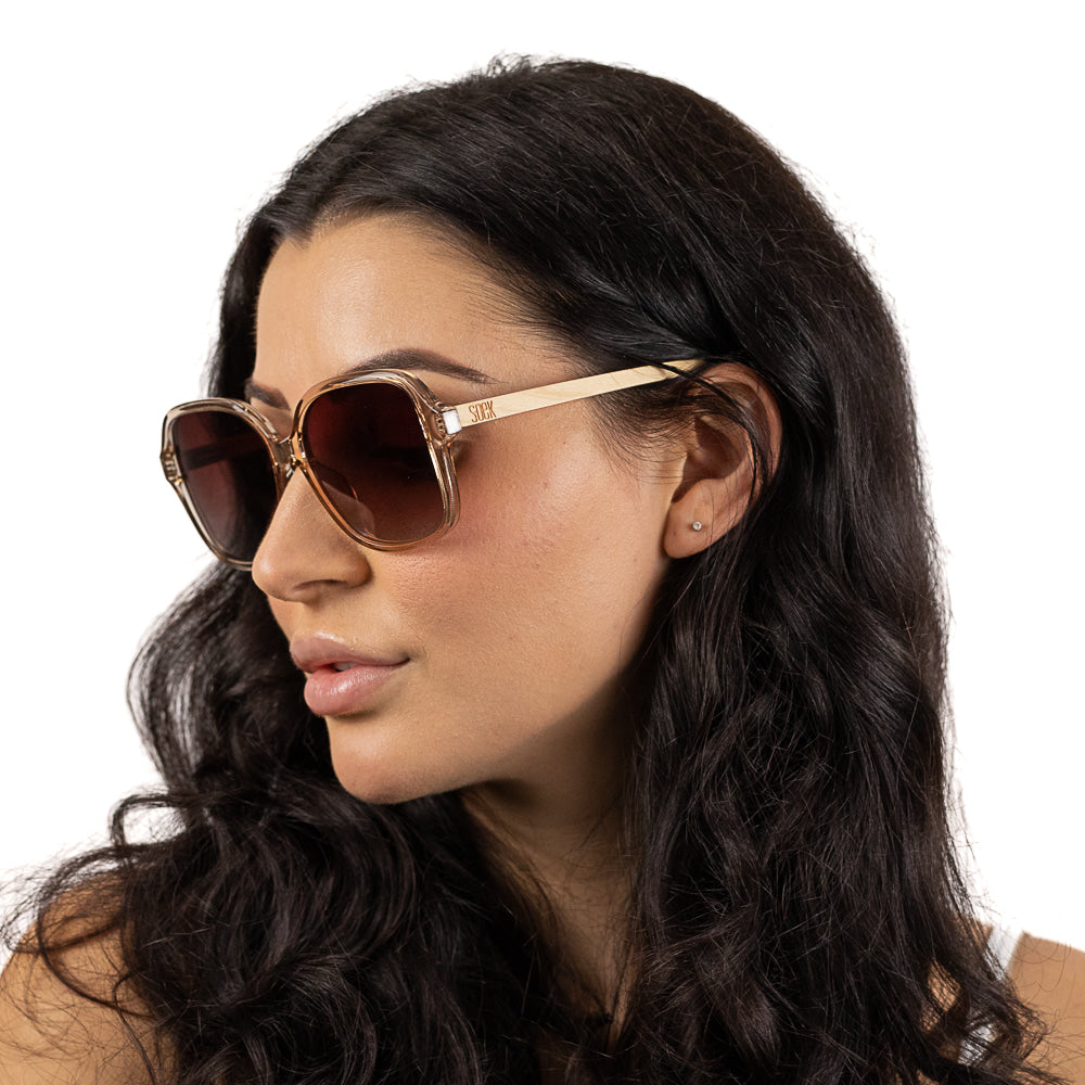 Three-quarter view of a dark-haired model wearing the Scarlett sunglasses, showing the Soek engraved maple arm