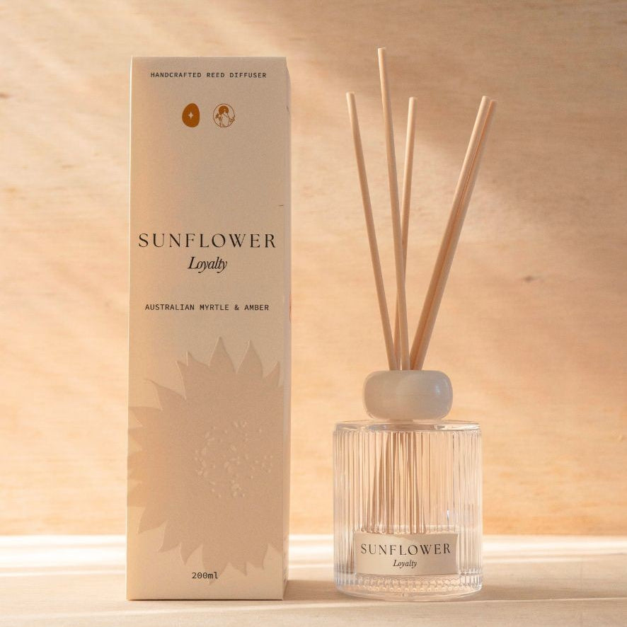 The Sunflower reed diffuser, a ribbed glass bottle with natural reeds, beside its cream box.