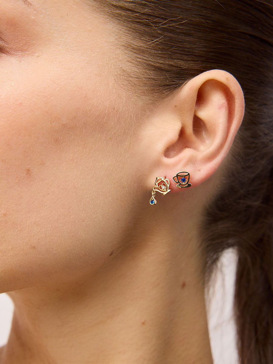 Close view of an ear wearing the teacup and teapot studs