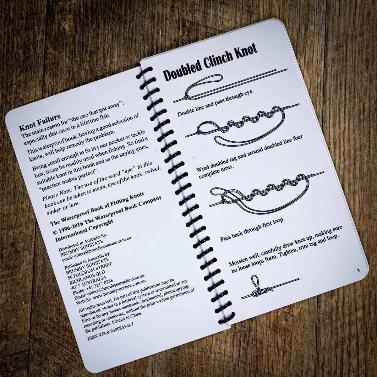 The spiral-bound book open at the Doubled Clinch Knot, with step-by-step drawings.