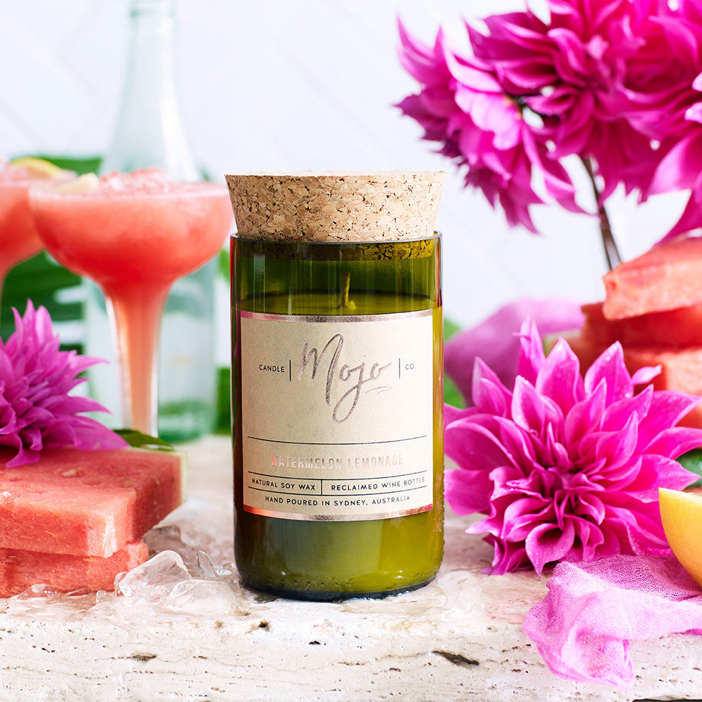 Watermelon Lemonade candle on ice beside a watermelon slushie and magenta dahlias