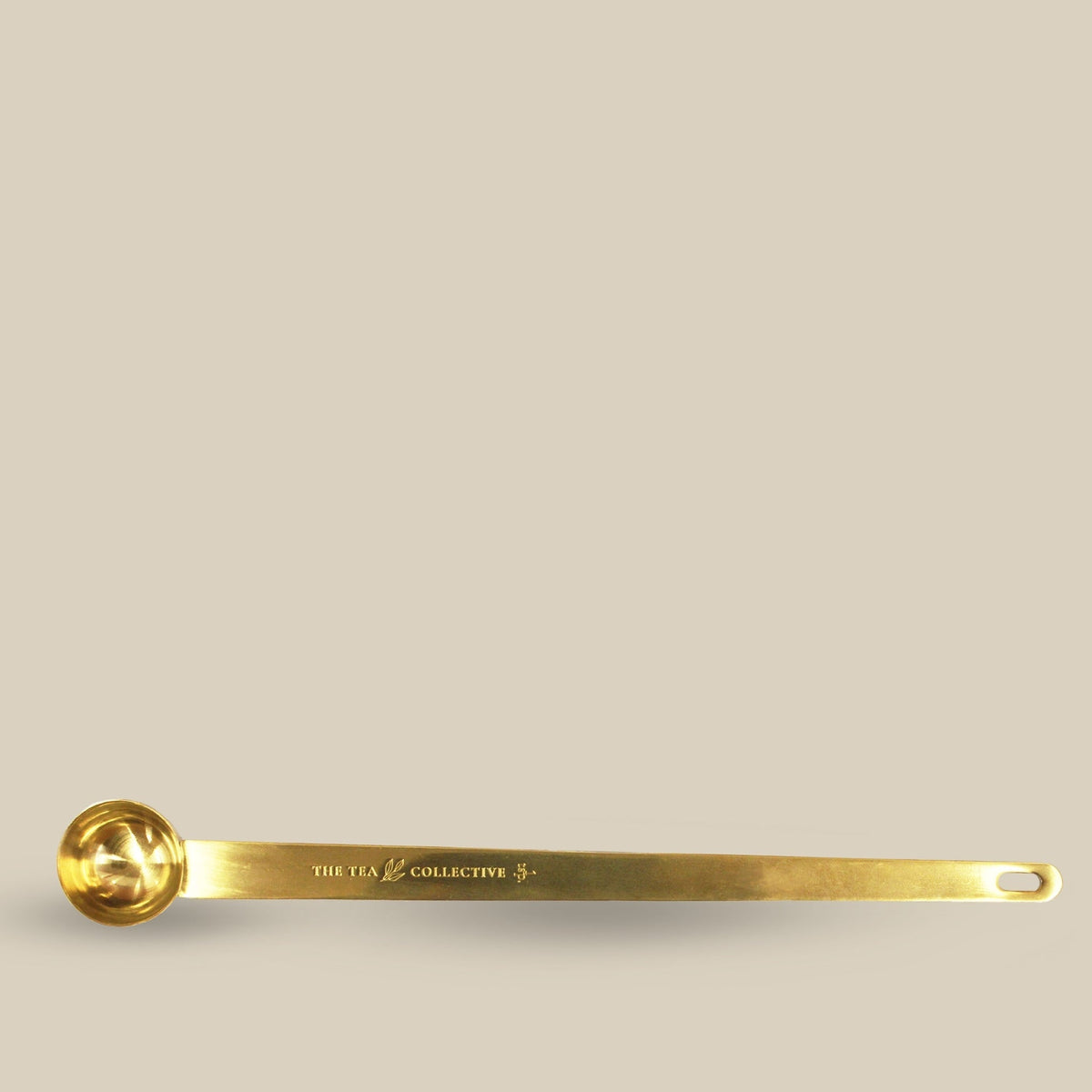 Long gold tea spoon engraved with The Tea Collective branding