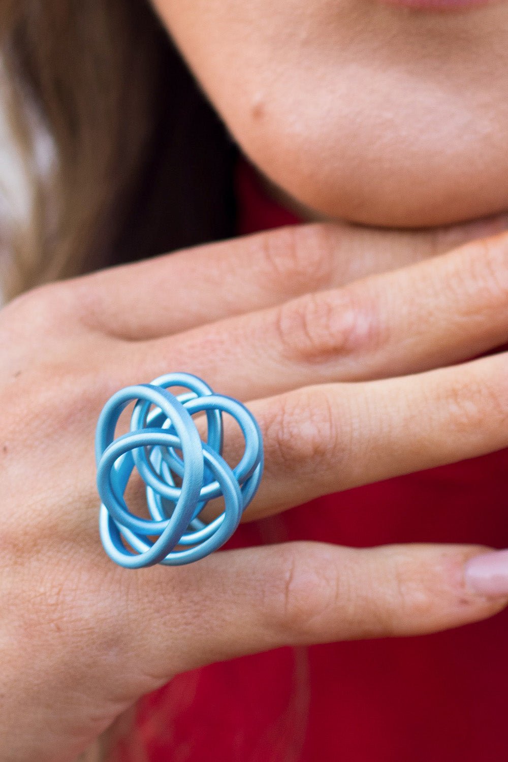 Twisted sky blue aluminium Monica scrunch ring worn on a finger