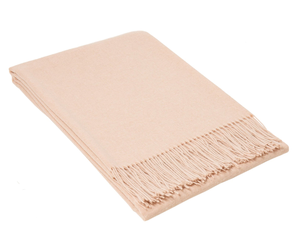 Blush pink merino wool blend throw folded neatly with a knotted fringe along one edge