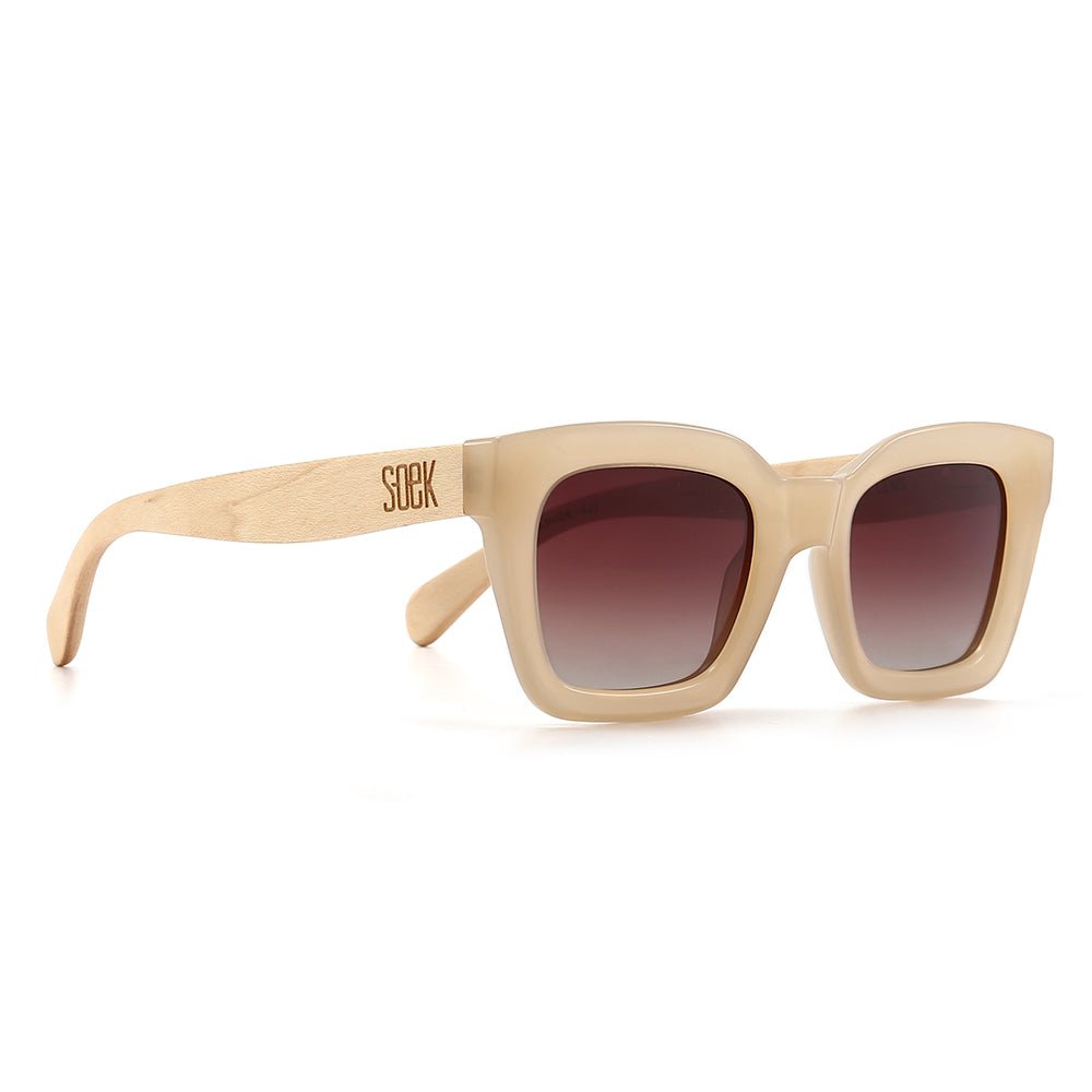 Zahra sunglasses in nude at an angle, a cream square frame with pale wood arms and brown gradient lenses