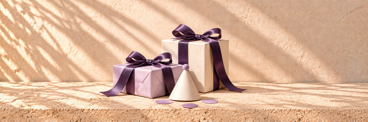 Ivory and lavender parcels with purple satin and a small paper party hat in front