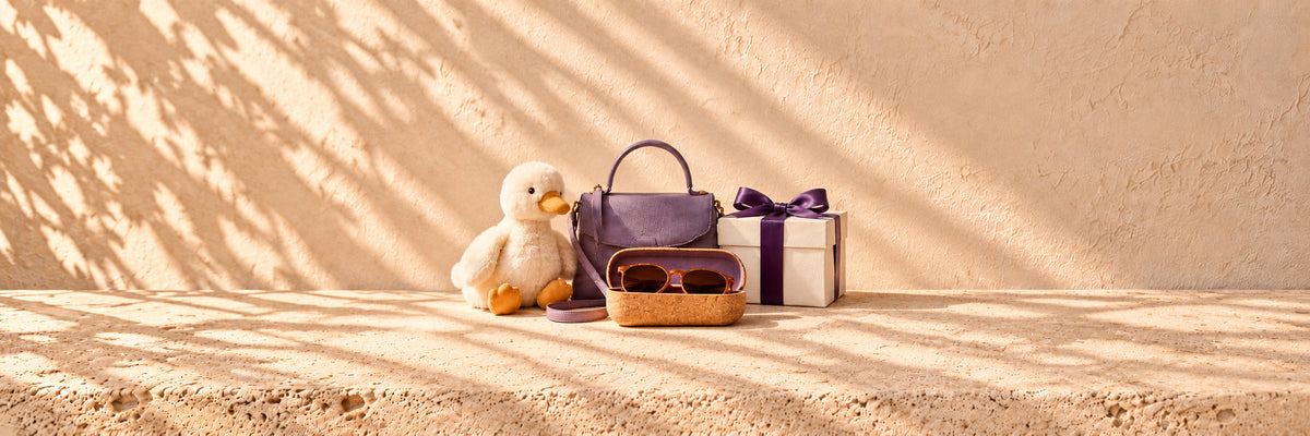 A plush duck, a lilac handbag, sunglasses in a cork case and a ribbon-tied gift box