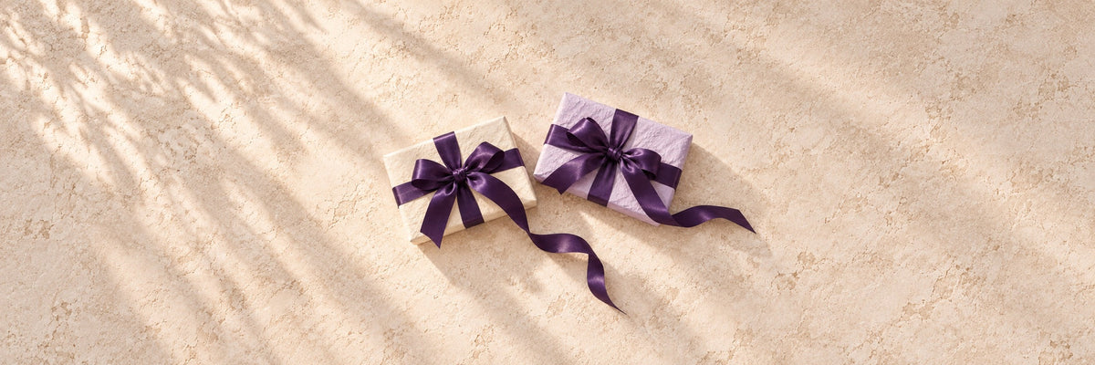 Kraft paper parcels tied with twine and lilac sprigs on whitewashed timber