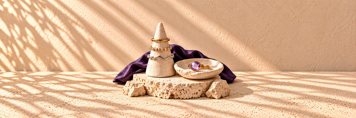 Gold and silver rings on a stone ring cone, with a purple stone ring in a small dish