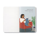 Open journal with lined pages beside an illustration of a woman reading in a red armchair with her dog