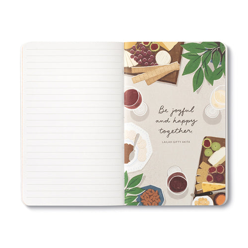 Open journal with lined pages beside an overhead grazing board and the words be joyful and happy together